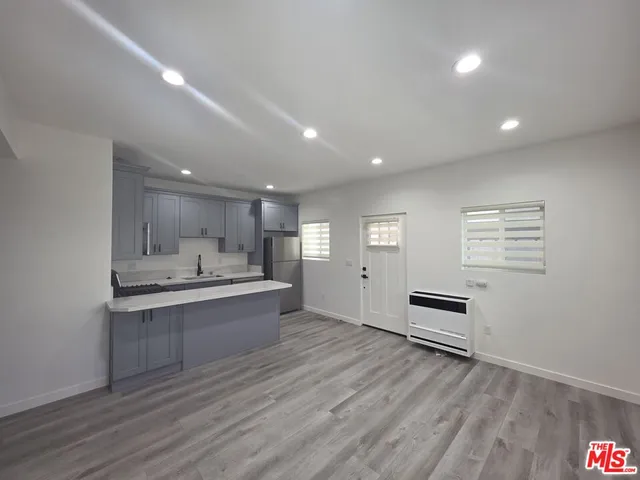 a large kitchen with stainless steel appliances a stove and wooden floor