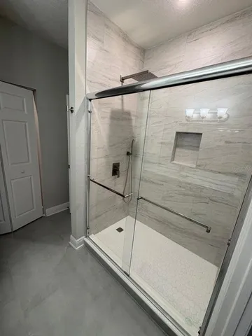 a bathroom with a glass door shower and closet