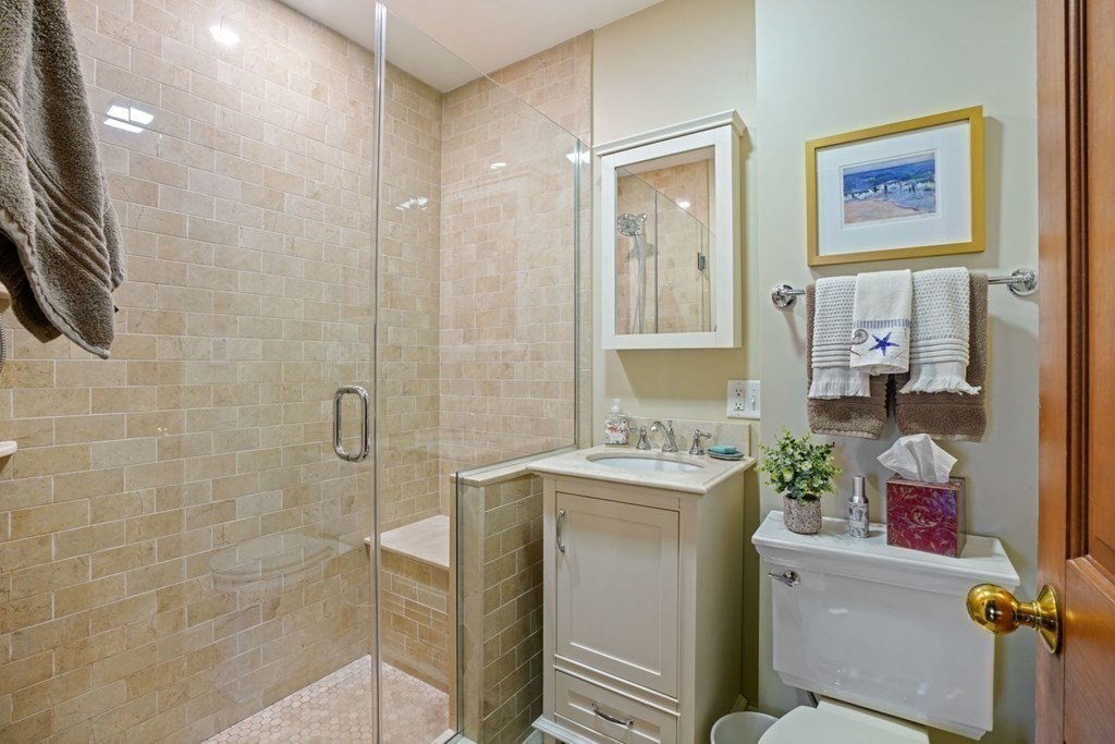 54 Olney Street Watertown, MA 02472 - Photo 21 of 28 a bathroom with a granite countertop sink a mirror a bathtub and shower