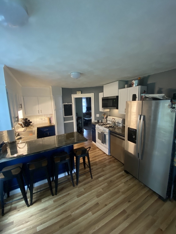 54 Olney Street Watertown, MA 02472 - Photo 5 of 28 a open kitchen with stainless steel appliances wooden floors and wooden cabinets