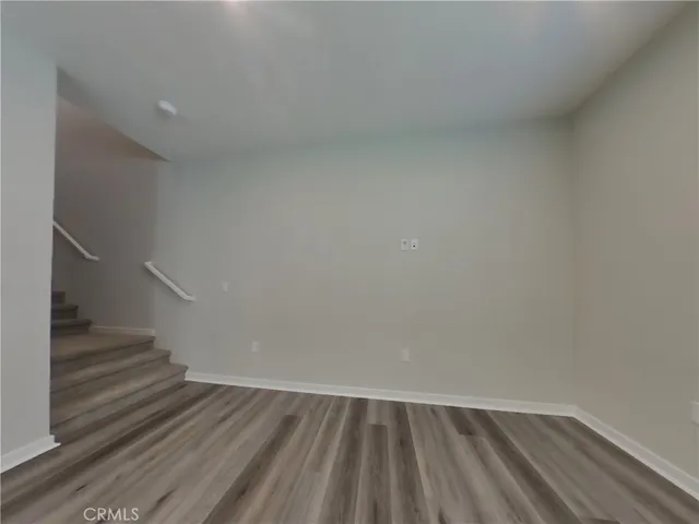 a view of an empty room with wooden floor and stairs