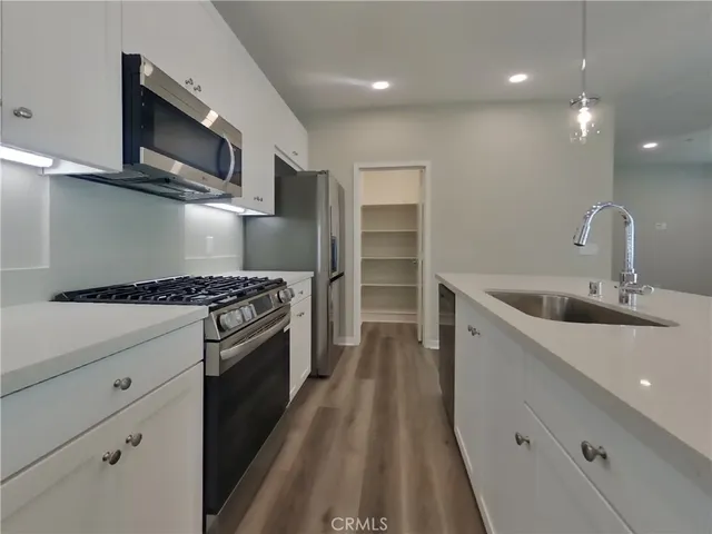 a kitchen with stainless steel appliances kitchen island granite countertop a sink a stove and a refrigerator