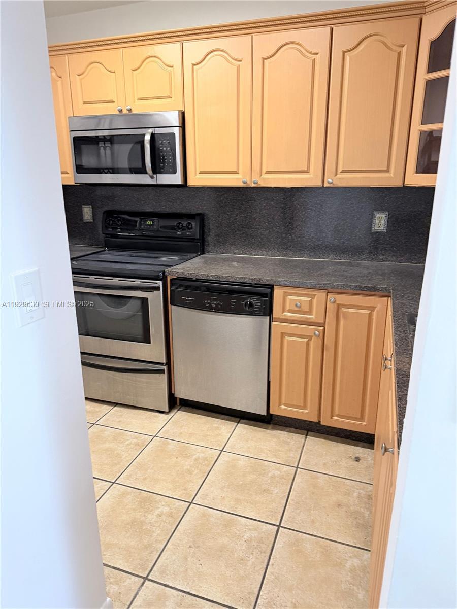 15312 Southwest 72nd Street, Unit 2112 Miami, FL 33193 - Photo 7 of 11 a kitchen with granite countertop a stove and a microwave