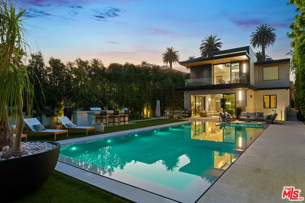a view of a swimming pool with chairs in front of house