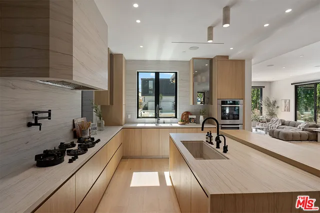 a large white kitchen with a large window and stainless steel appliances