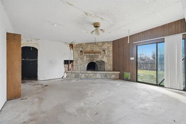 a view of an empty room with fireplace and a window