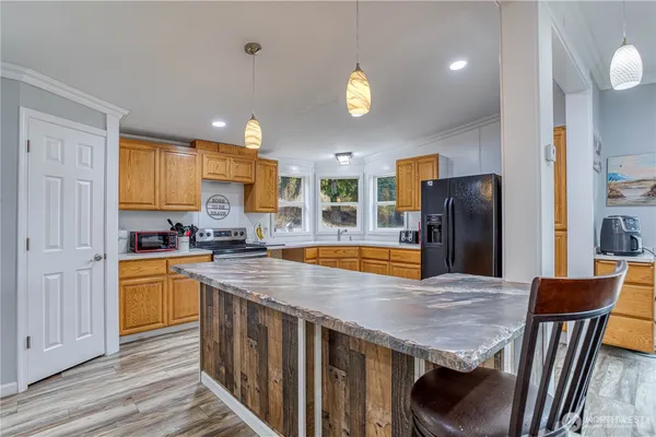 a kitchen with stainless steel appliances granite countertop a kitchen island a stove a refrigerator a sink a dining table and chairs