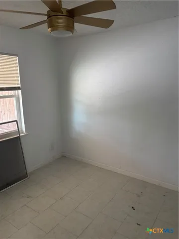 an empty room with windows and ceiling fan