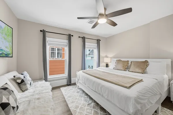 a bedroom with a large bed and two windows