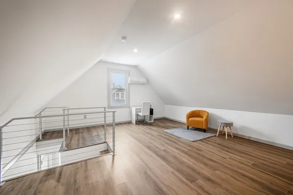 an empty room with wooden floor and lounge chair