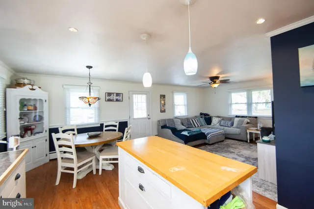 a living room with lots of furniture kitchen view and a wooden floor