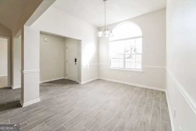 an empty room with wooden floor cabinet and windows