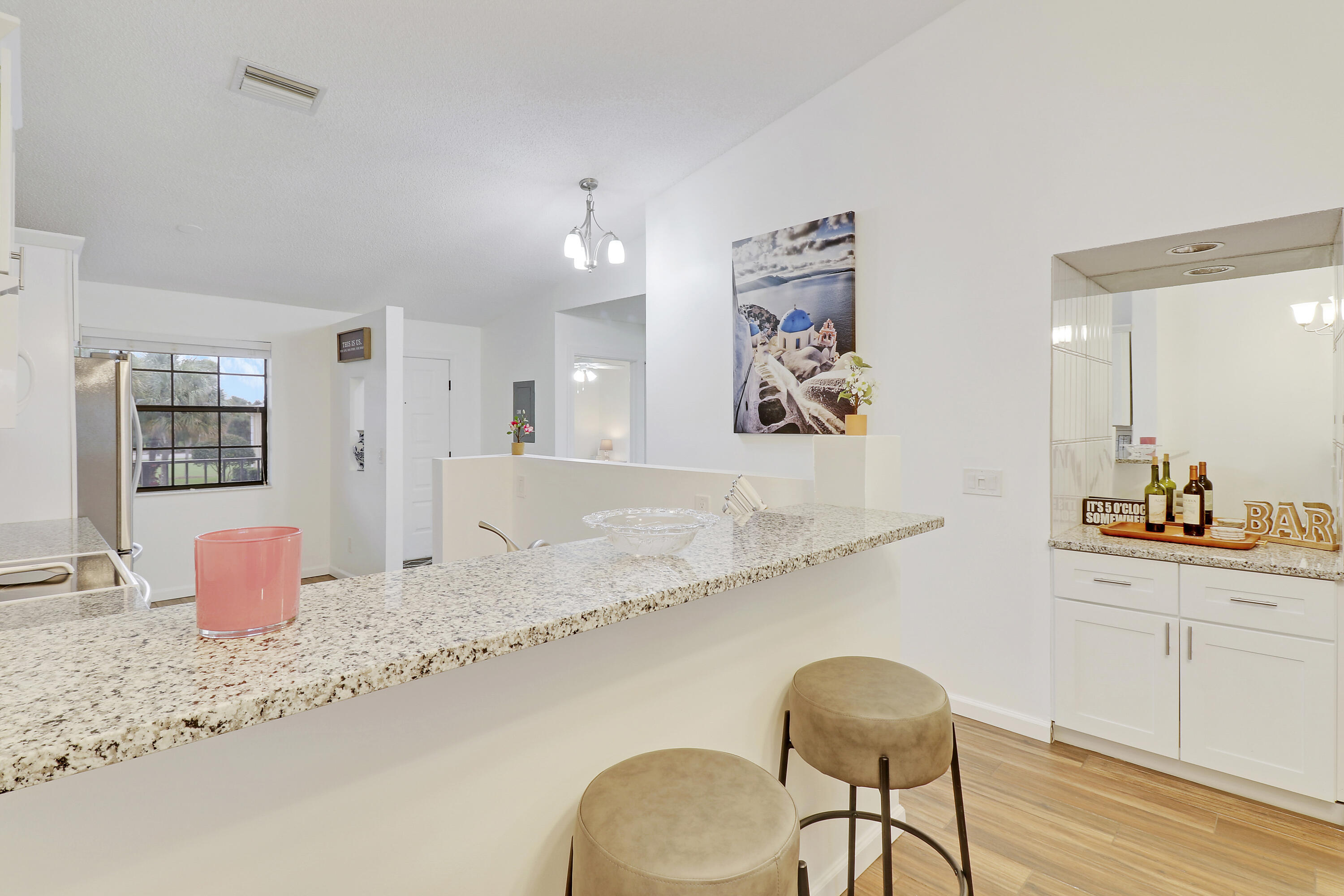 1112 Keystone Drive, Unit A Jupiter, FL 33458 - Photo 12 of 41 a kitchen with stainless steel appliances kitchen island granite countertop a dining table chairs and a refrigerator a sink with wooden floor