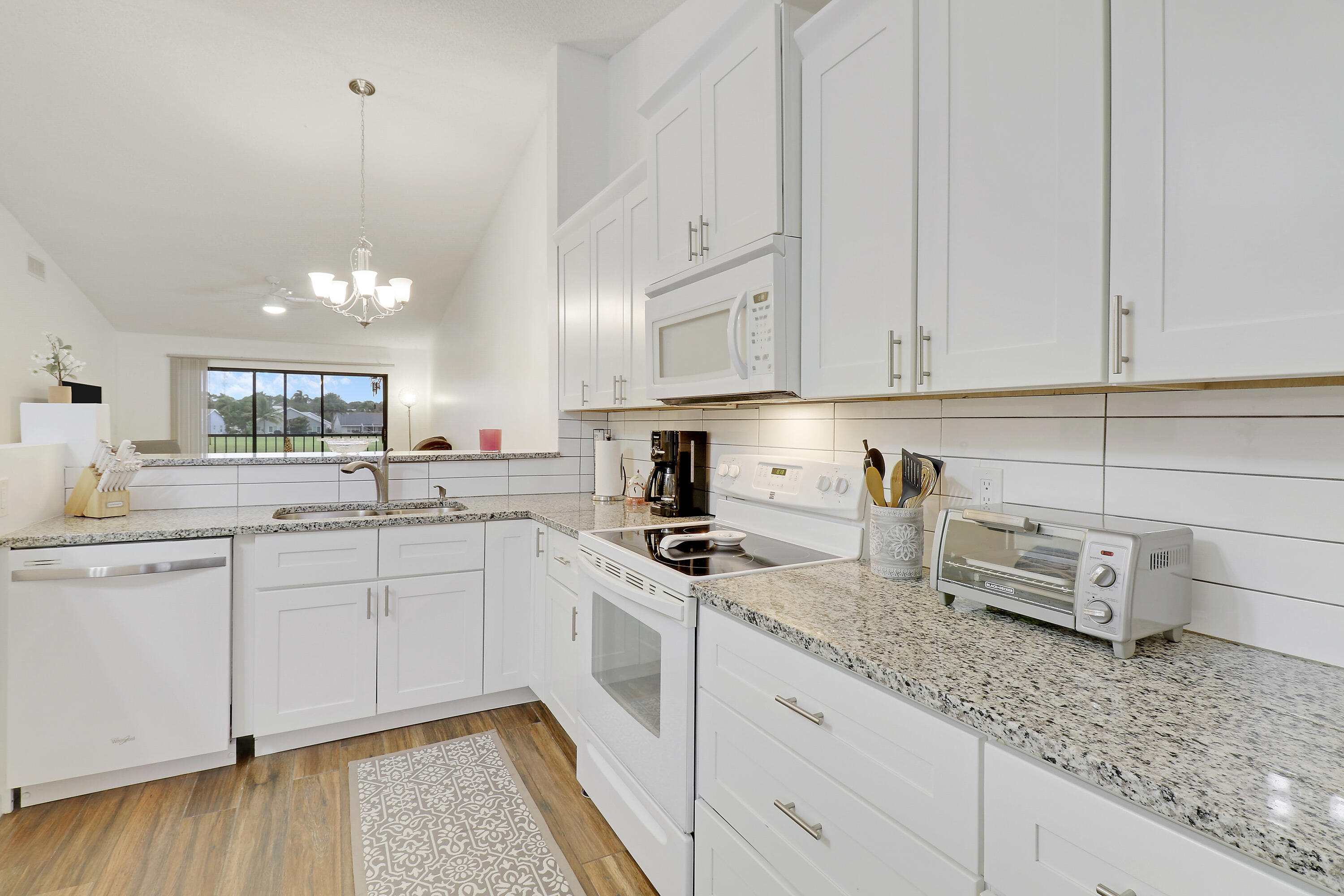 1112 Keystone Drive, Unit A Jupiter, FL 33458 - Photo 17 of 41 a kitchen with granite countertop white cabinets and white appliances