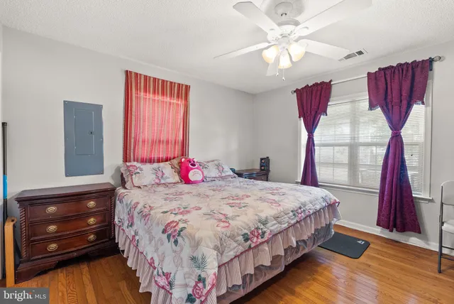 a bedroom with a bed and a dresser with wooden floor