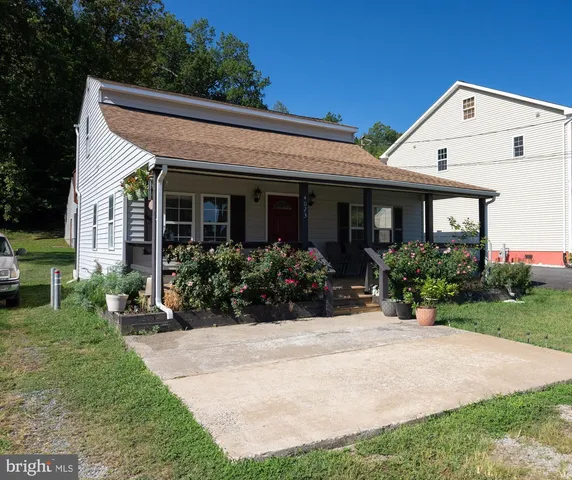 a view of a white house with a big yard and potted plants