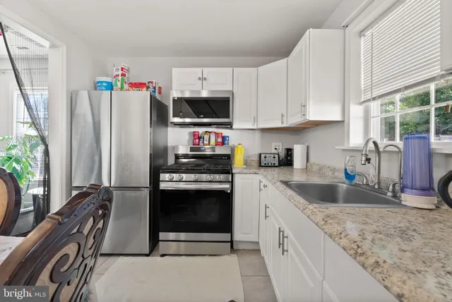 a kitchen with granite countertop a refrigerator stove and sink