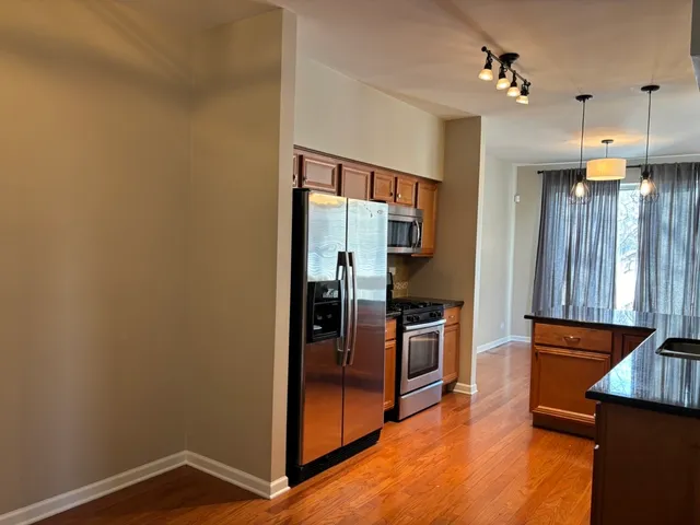 a view of a kitchen with refrigerator and wooden floor