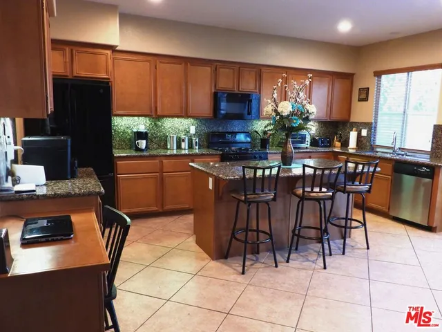 a kitchen with stainless steel appliances kitchen island granite countertop a table chairs and a refrigerator