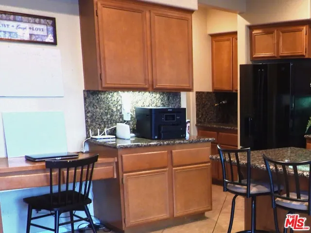 a room with stainless steel appliances kitchen island granite countertop a refrigerator a stove a sink dishwasher with a dining table and chairs