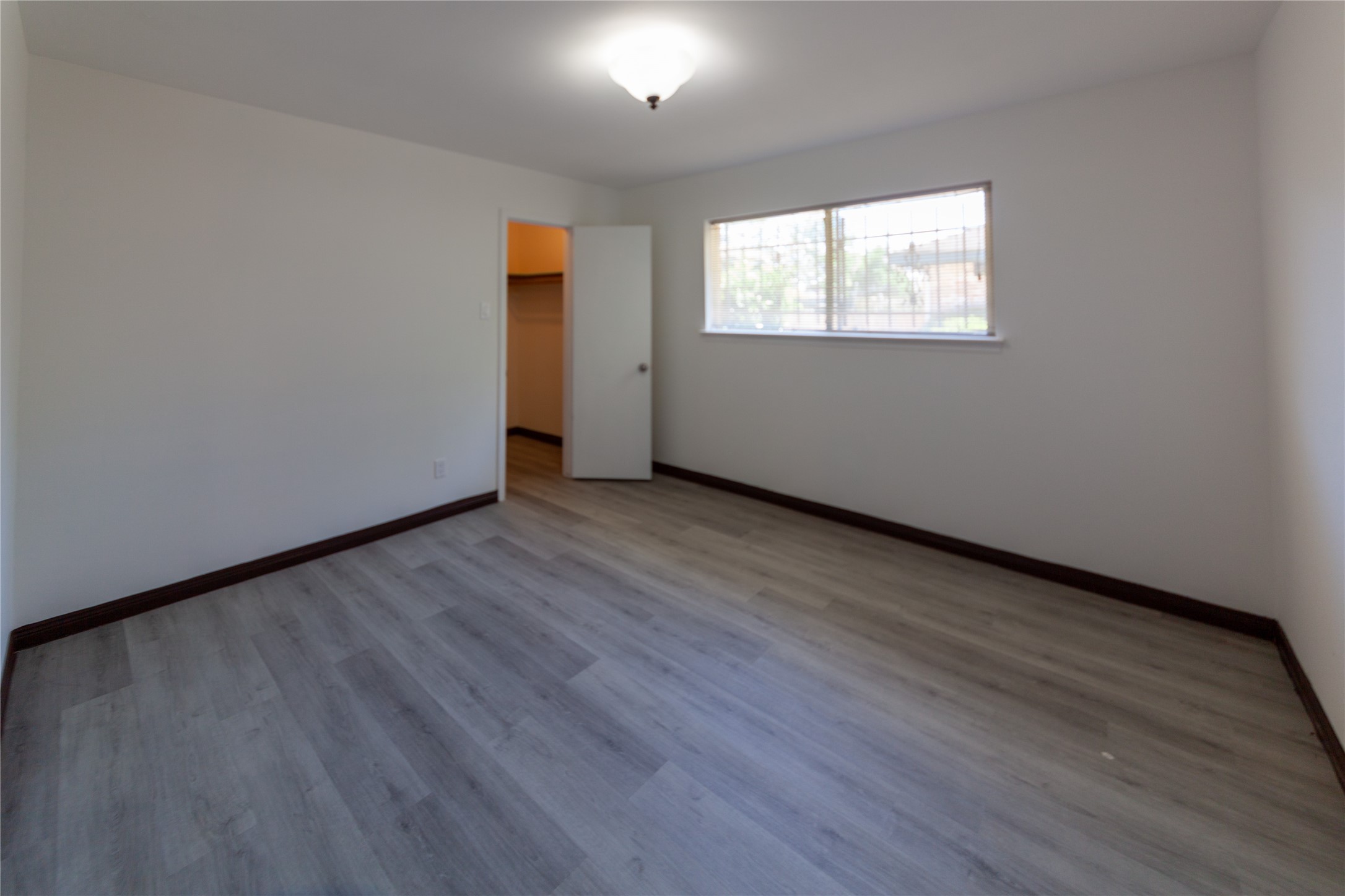 8826 Roos Road Houston, TX 77036 - Photo 22 of 42 A bright, spacious bed room 3 with light wood flooring, white walls, and a large window for natural light. It features a closet with an open door, and a ceiling light fixture.