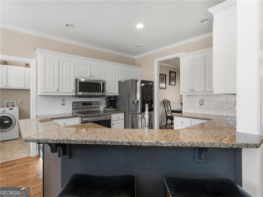 355 Parker Road Covington, GA 30014 - Photo 26 of 60 a kitchen with granite countertop a sink white cabinets and stainless steel appliances