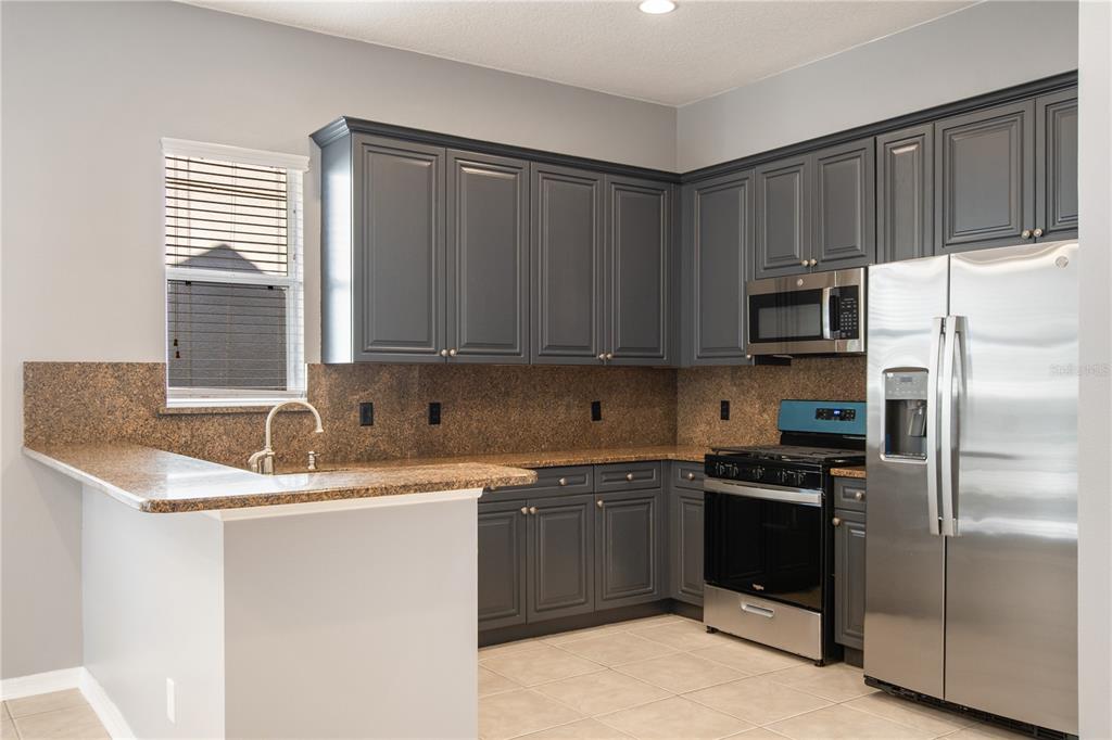 13118 Sunkiss Loop Windermere, FL 34786 - Photo 14 of 52 a kitchen with stainless steel appliances granite countertop a sink stove refrigerator and cabinets