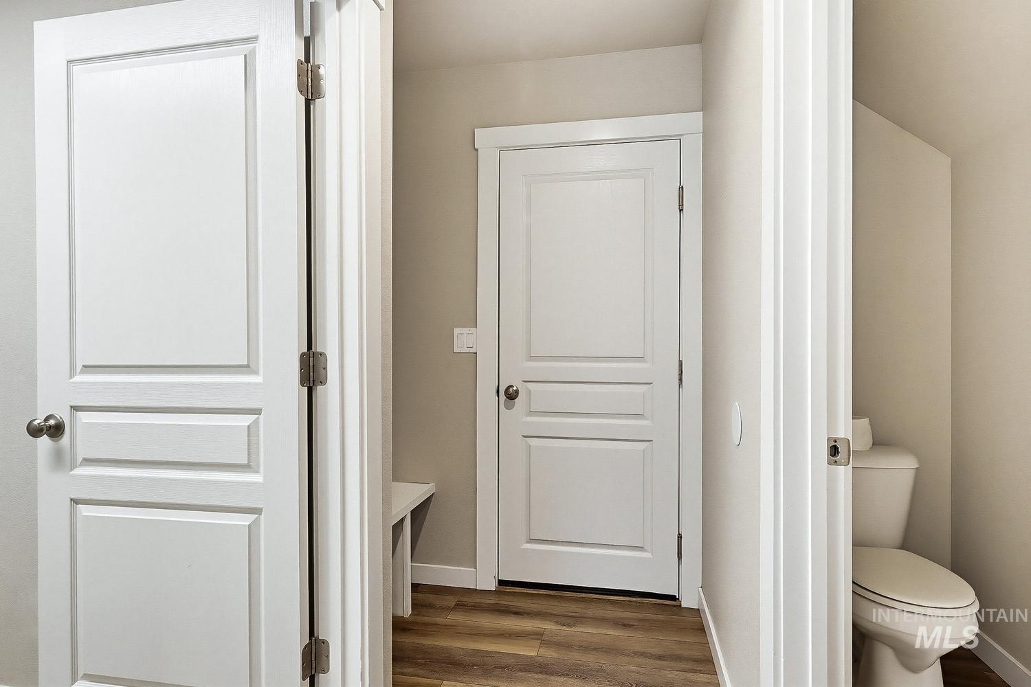 846 North Hidden View Way Star, ID 83669 - Photo 23 of 49 Interior hallway featuring white paneled doors, neutral wall tones, and wood-finish flooring