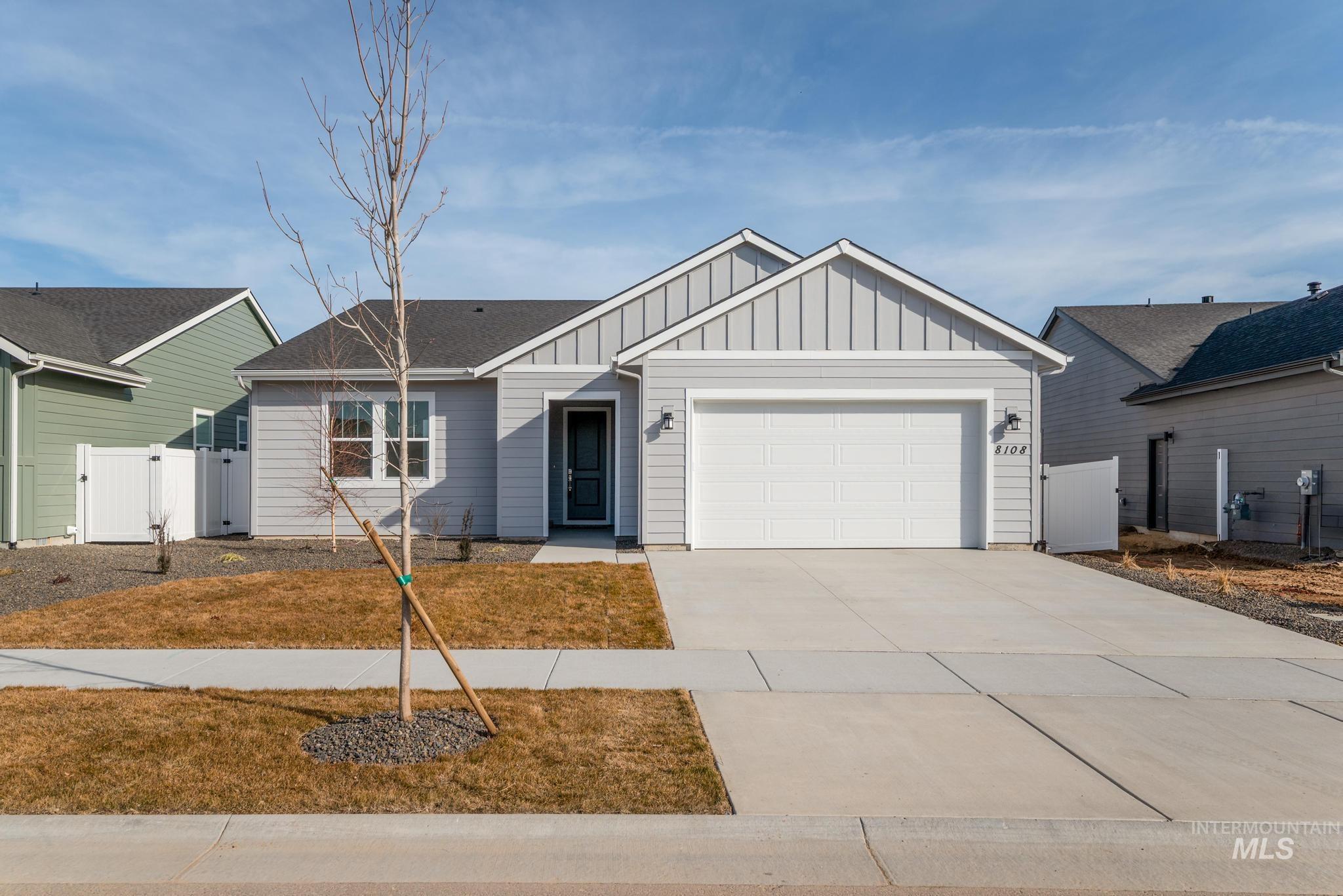 View of front of house with a gate, board and batten siding, a garage, and concrete driveway