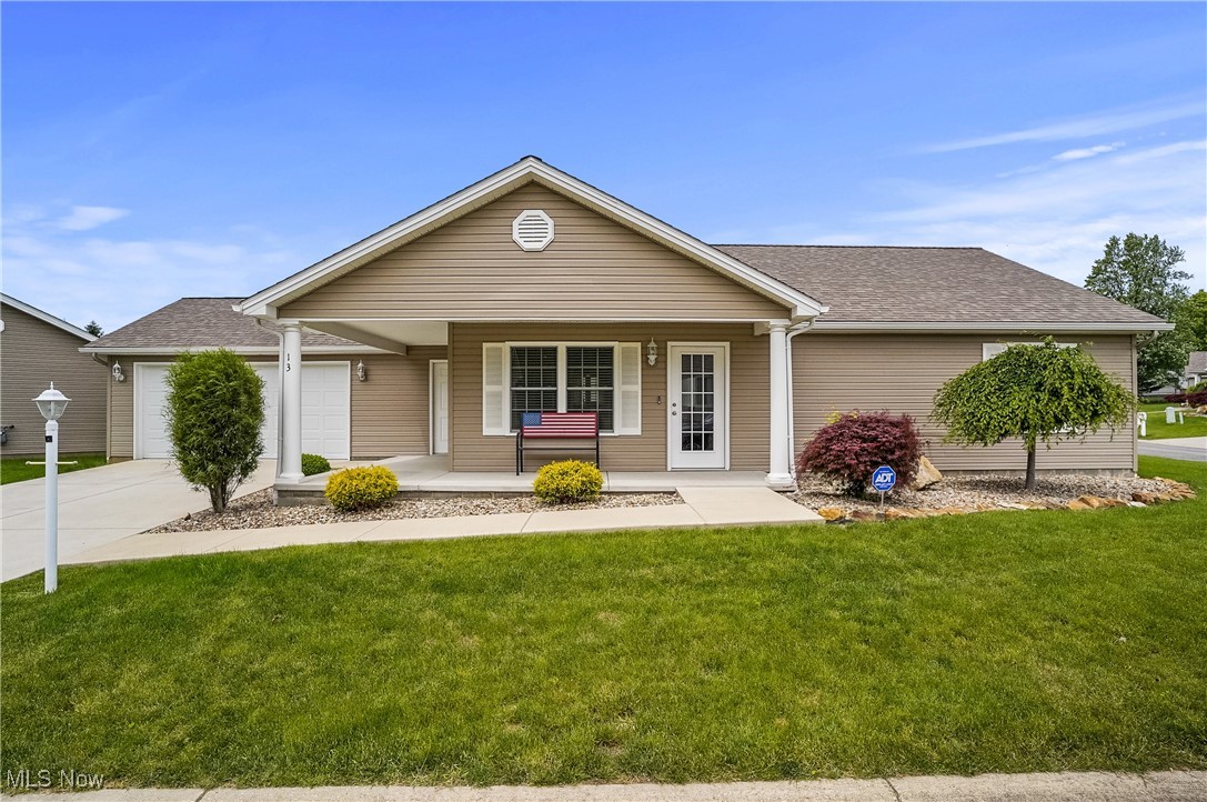 Single story home featuring a garage, a porch, a front lawn, driveway, and a shingled roof