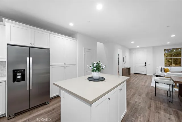 a kitchen with stainless steel appliances a dining table chairs and refrigerator