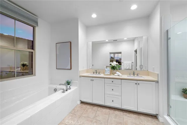 a bathroom with a bathtub a double vanity sink and mirror