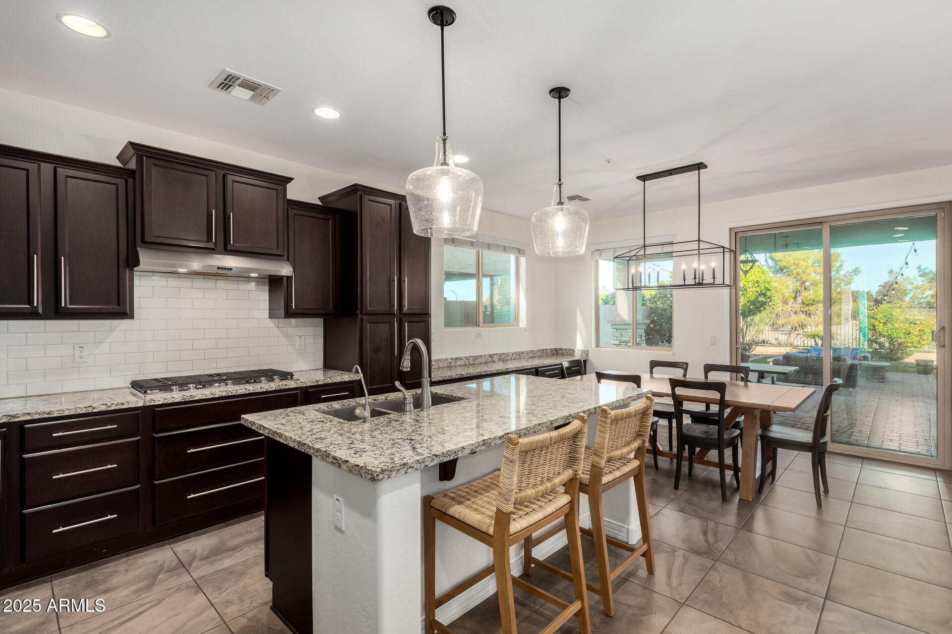 3420 East Indigo Street Gilbert, AZ 85298 - Photo 2 of 27 a kitchen with stainless steel appliances granite countertop a stove a refrigerator a sink a dining table and chairs with wooden floor