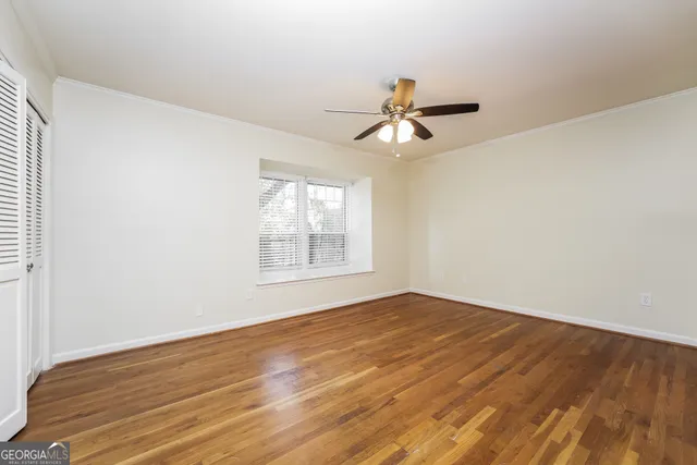 a view of empty room with wooden floor and fan