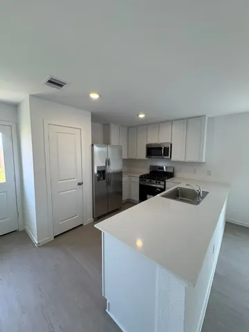 a kitchen with a refrigerator a stove top oven a sink and cabinets