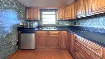 a kitchen with stainless steel appliances granite countertop wooden cabinets a sink and dishwasher with wooden floor