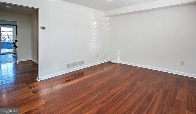 a view of a hallway with wooden floor and a living room