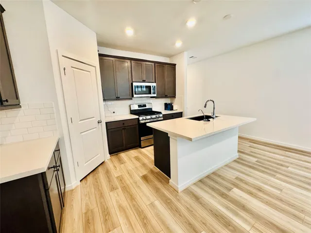 a kitchen with a sink and a stove top oven with wooden floor