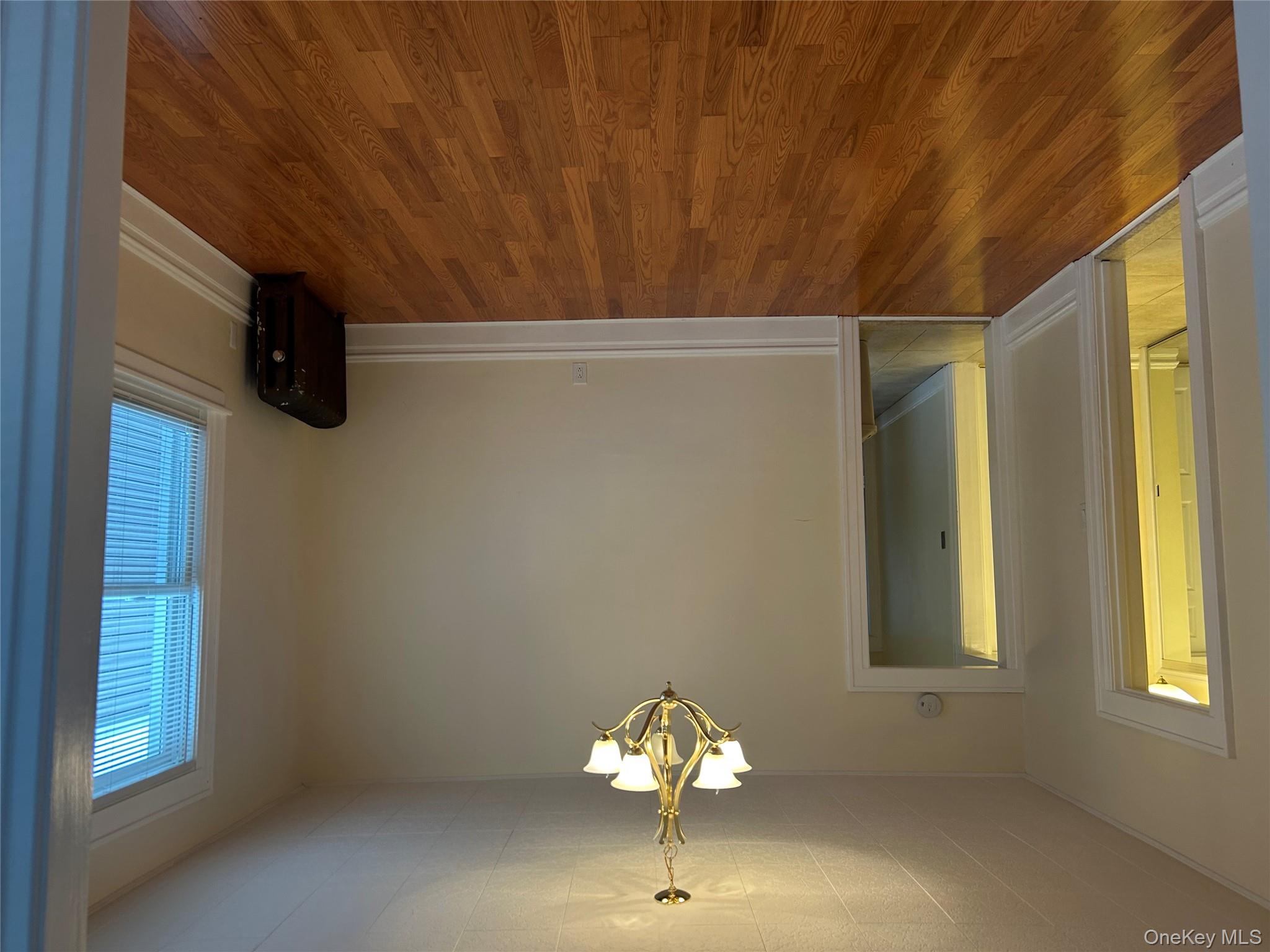 Unfurnished room with wood finished floors and a chandelier