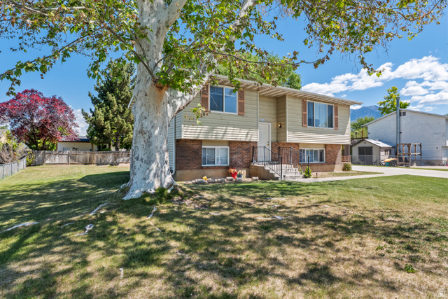 2402 710 North Provo, UT 84601 - Photo 2 of 15 Split-level residence featuring a brick and siding exterior, front porch with wrought iron railings, and mature landscaping