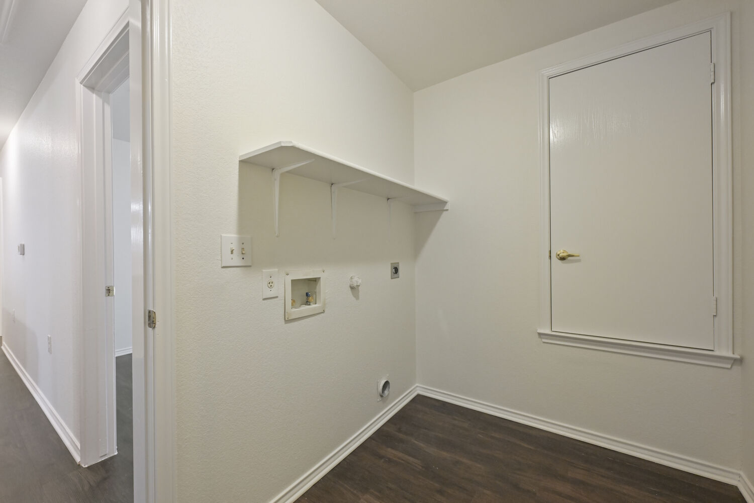 6733 Doyal Drive Austin, TX 78747 - Photo 14 of 28 A well-appointed utility room features a built-in shelf and dark wood flooring, ready for laundry.