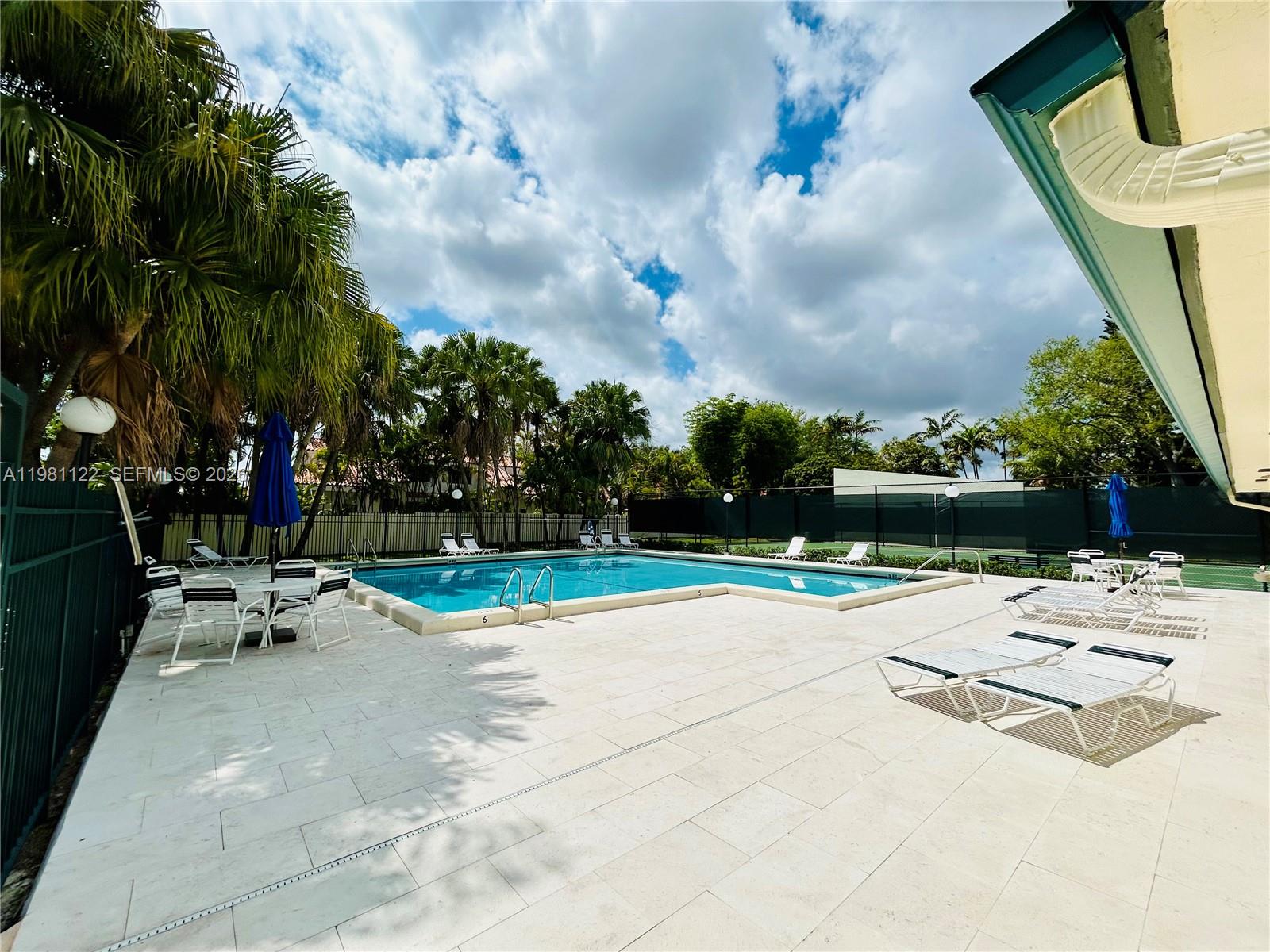 10818 Southwest 72nd Street, Unit 154 Miami, FL 33173 - Photo 22 of 28 a view of pool with lawn chairs and palm tree