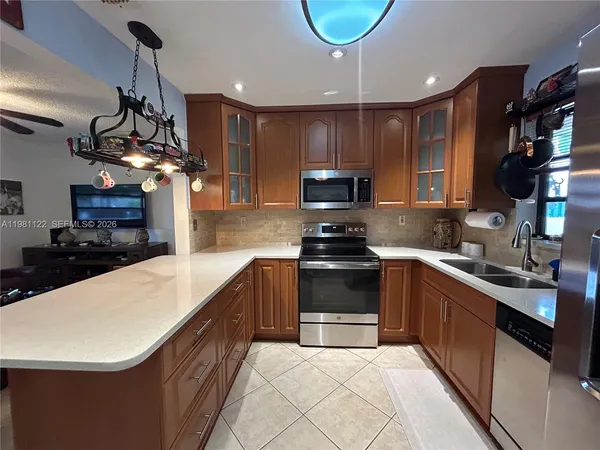 a kitchen with stainless steel appliances granite countertop a refrigerator a sink a stove and cabinets