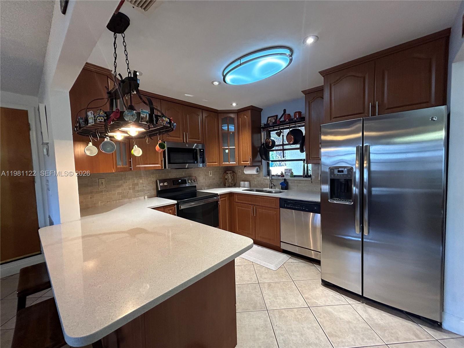 10818 Southwest 72nd Street, Unit 154 Miami, FL 33173 - Photo 5 of 28 a kitchen with stainless steel appliances granite countertop a refrigerator a sink a stove and cabinets