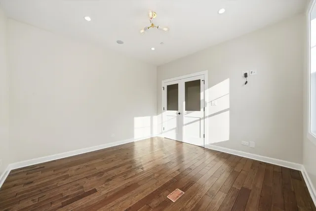 a view of an empty room with window and wooden floor