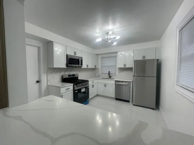 a kitchen with a refrigerator a sink and a stove top oven with white cabinets