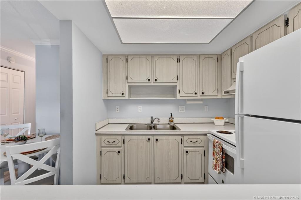 2929 Southeast Ocean Boulevard, Unit J3 Stuart, FL 34996 - Photo 19 of 65 a kitchen with stainless steel appliances granite countertop a refrigerator sink and white cabinets