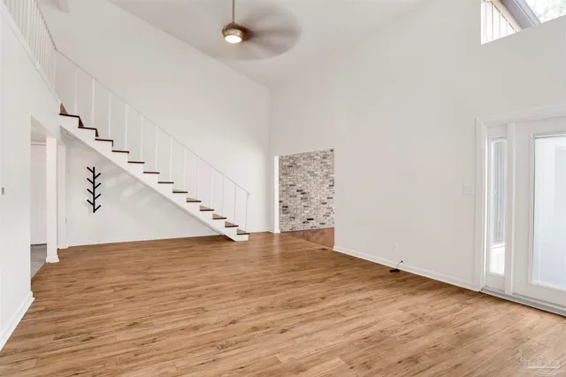 a view of an empty room with wooden floor and staircase