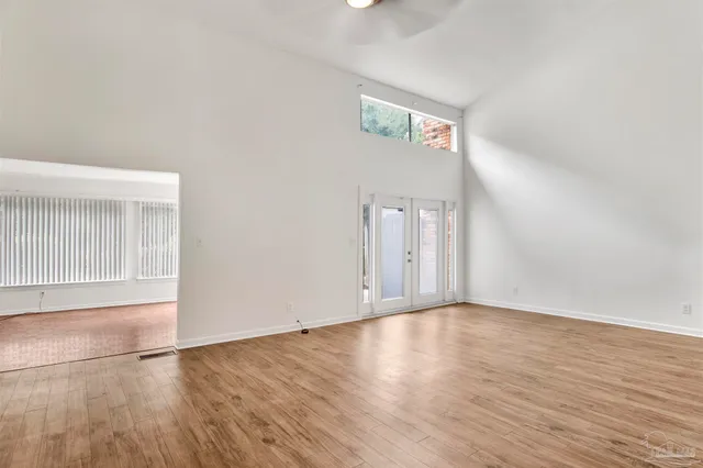 an empty room with wooden floor and windows