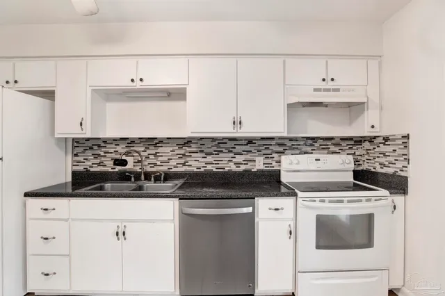 a kitchen with stainless steel appliances granite countertop white cabinets and a sink